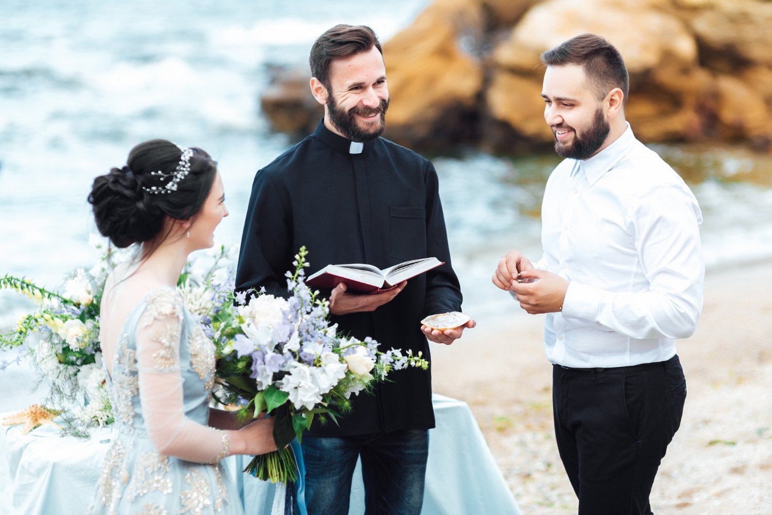 wedding couple near the ocean with a priest
